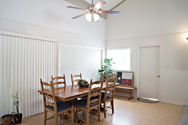 dining room featuring light wood-style floors, a high ceiling, and a ceiling fan