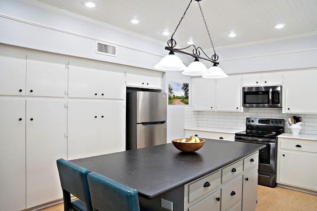 kitchen featuring visible vents, decorative backsplash, light wood-style flooring, ornamental molding, and stainless steel appliances