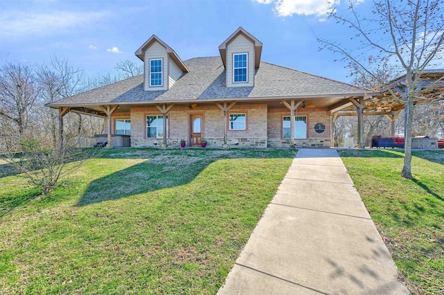 view of front of property with brick siding, a front lawn, and roof with shingles