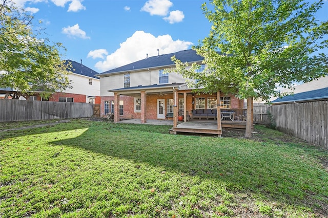 rear view of house with brick siding, a lawn, a fenced backyard, and a wooden deck