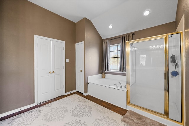 bathroom with vaulted ceiling, a shower stall, wood finished floors, baseboards, and a bath