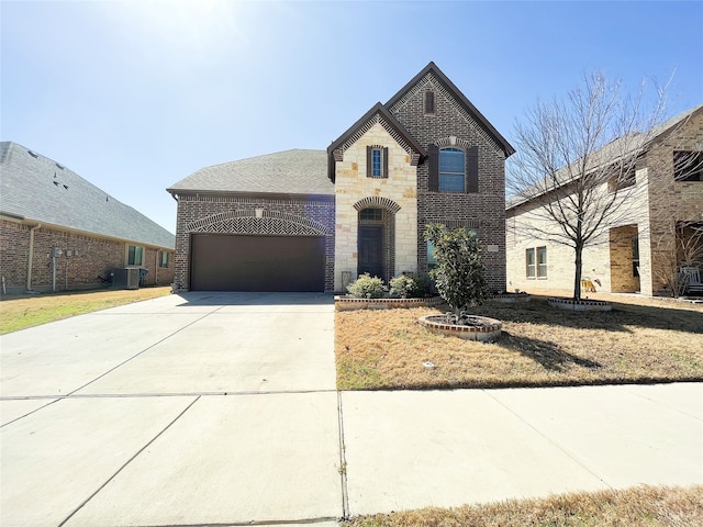 french country style house featuring driveway, stone siding, an attached garage, central air condition unit, and brick siding