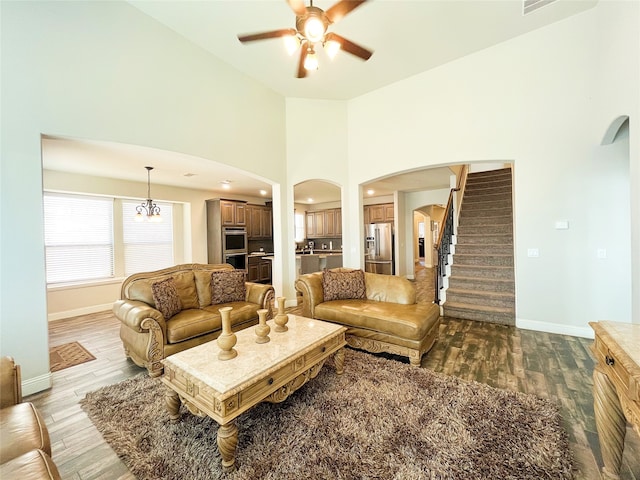 living area with arched walkways, wood finished floors, stairs, and baseboards