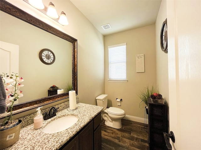 bathroom featuring toilet, wood finished floors, vanity, visible vents, and baseboards