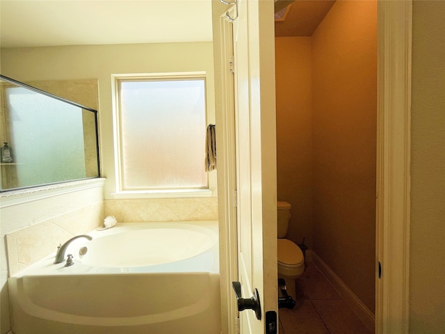 full bathroom featuring tile patterned flooring, baseboards, a garden tub, and toilet