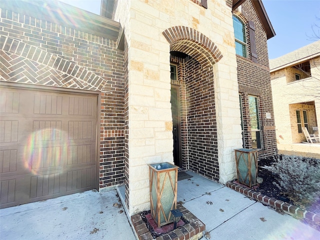 doorway to property with stone siding, brick siding, and an attached garage