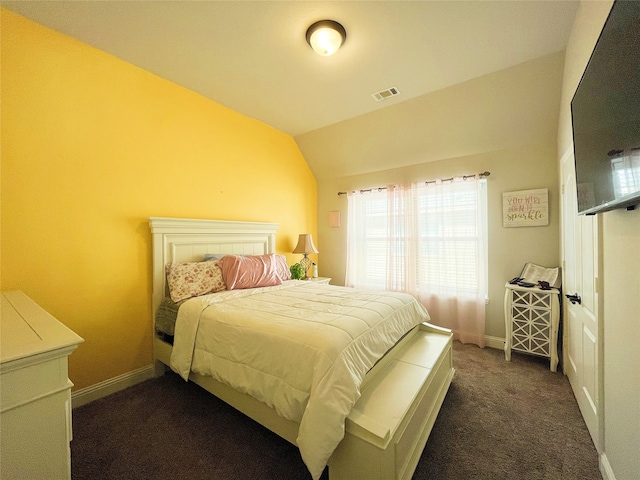 bedroom with lofted ceiling, dark colored carpet, visible vents, and baseboards