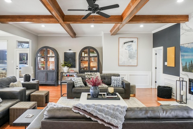 living area featuring beamed ceiling, a wainscoted wall, coffered ceiling, and wood finished floors