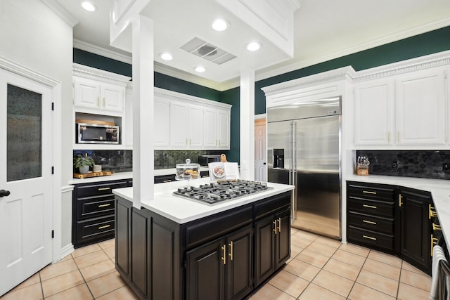 kitchen featuring visible vents, dark cabinetry, white cabinetry, light tile patterned floors, and built in appliances