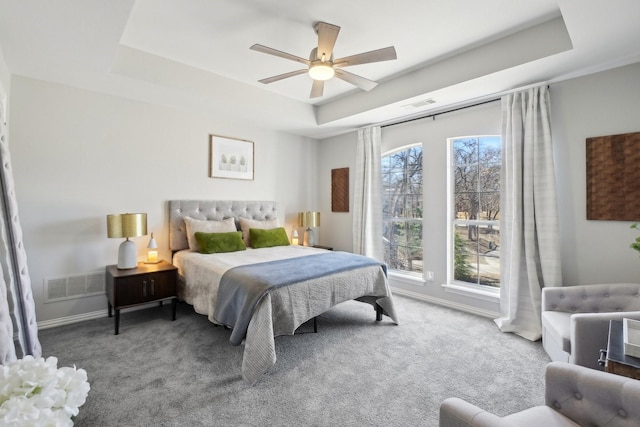 carpeted bedroom featuring visible vents, a raised ceiling, and baseboards