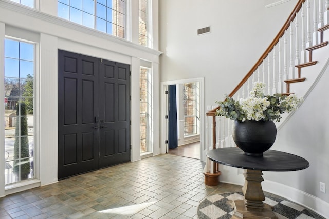 foyer featuring visible vents, a towering ceiling, and stairway