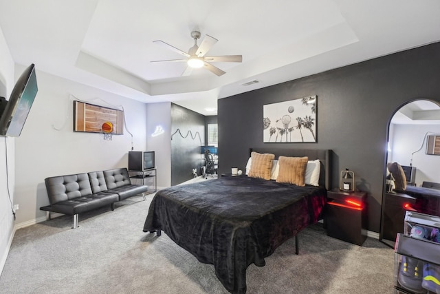 bedroom with a tray ceiling, carpet flooring, and visible vents