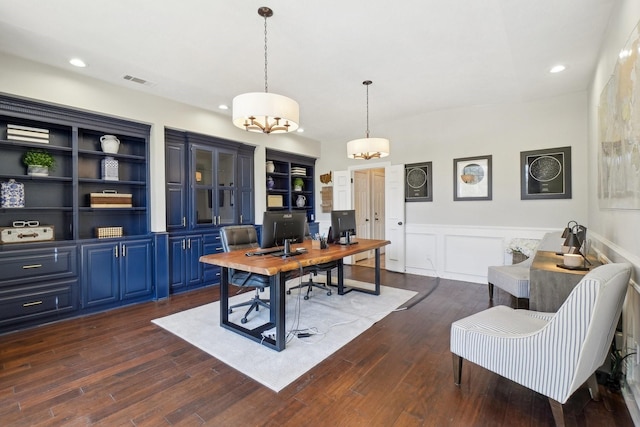 home office featuring visible vents, wainscoting, a decorative wall, and dark wood-style flooring