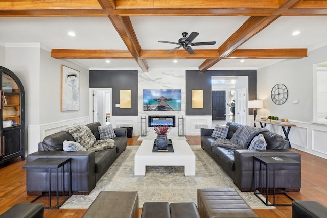 living room featuring wood finished floors, coffered ceiling, beam ceiling, a decorative wall, and a large fireplace