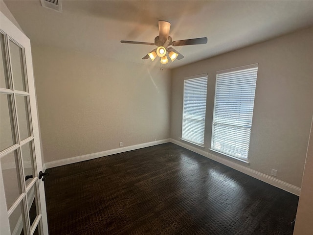 unfurnished room featuring dark wood-type flooring, visible vents, ceiling fan, and baseboards