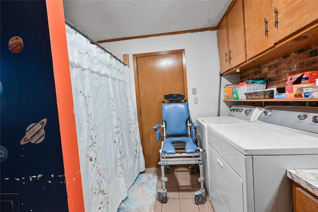 laundry area featuring a textured ceiling, light tile patterned floors, separate washer and dryer, cabinet space, and crown molding