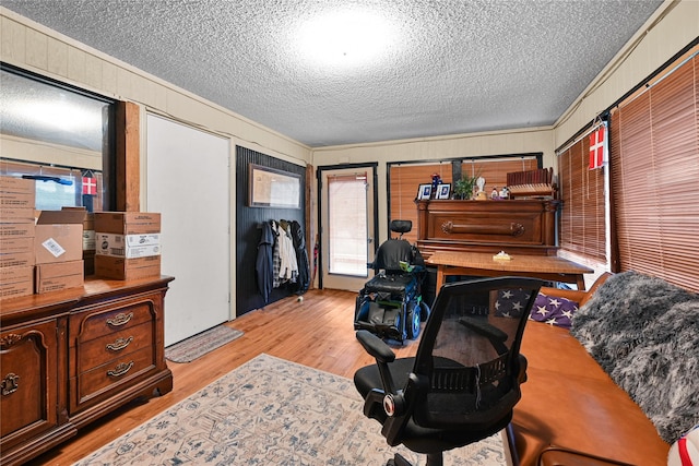 office featuring a textured ceiling, ornamental molding, and light wood-style flooring