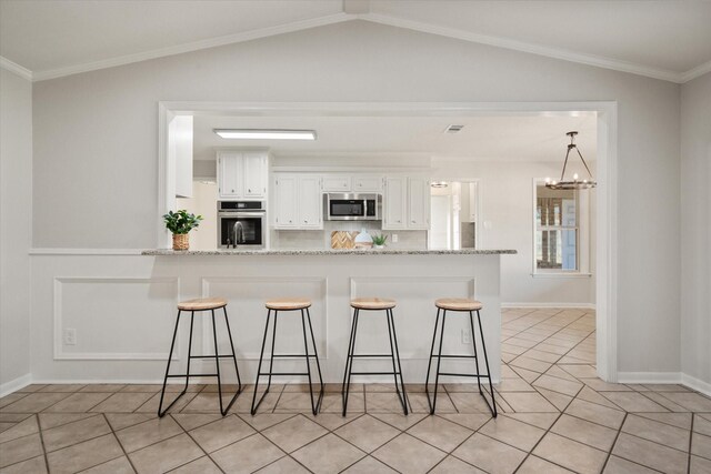 2013 Glenwood Cir, Corsicana, TX 75110 - kitchen featuring appliances with stainless steel finishes, white cabinets, a kitchen breakfast bar, a chandelier, and lofted ceiling
