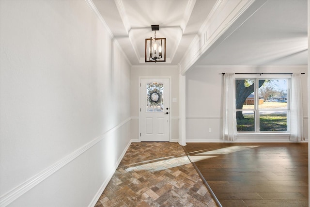 foyer with baseboards, a healthy amount of sunlight, a chandelier, and crown molding