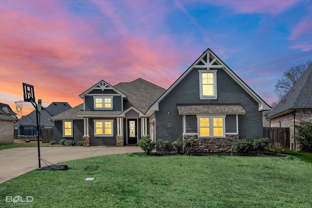 view of front of house with a yard, a trampoline, concrete driveway, and fence