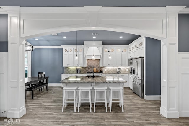 kitchen with backsplash, a breakfast bar, dark stone countertops, appliances with stainless steel finishes, and wood finished floors