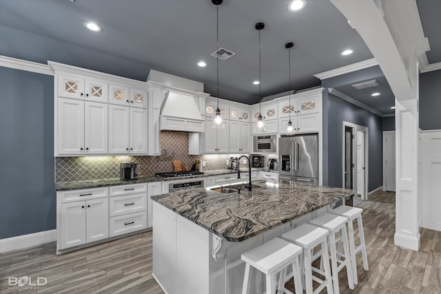 kitchen featuring premium range hood, a sink, appliances with stainless steel finishes, white cabinets, and wood tiled floor