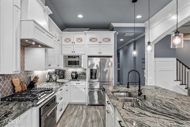 kitchen featuring premium range hood, a sink, stainless steel appliances, white cabinets, and tasteful backsplash