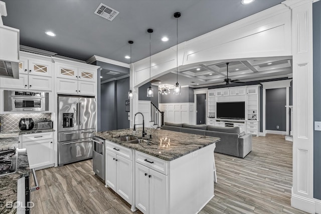 kitchen featuring visible vents, appliances with stainless steel finishes, arched walkways, a ceiling fan, and a sink