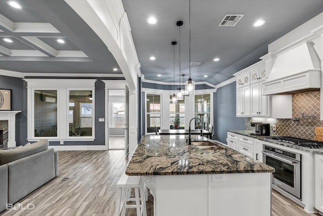 kitchen with visible vents, a sink, stainless steel appliances, white cabinets, and custom exhaust hood