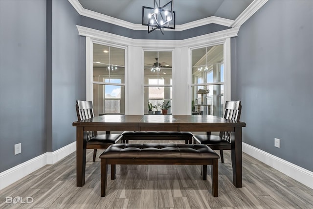 dining area featuring ceiling fan with notable chandelier, wood finished floors, crown molding, baseboards, and vaulted ceiling