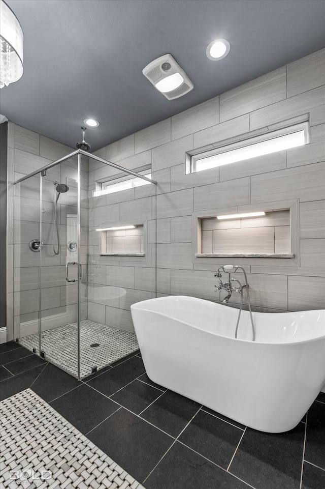 full bath featuring tile patterned floors, a shower stall, a freestanding bath, and tile walls