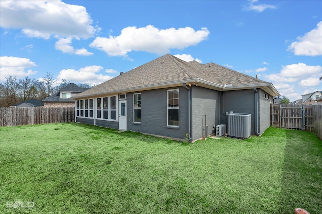 back of property with central air condition unit, a fenced backyard, a yard, a shingled roof, and brick siding