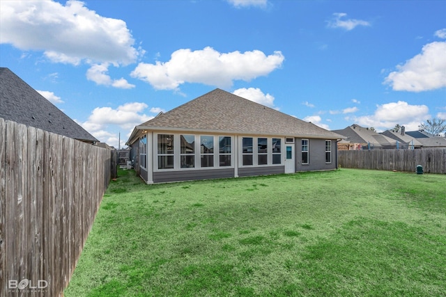 rear view of house featuring a yard, roof with shingles, and a fenced backyard