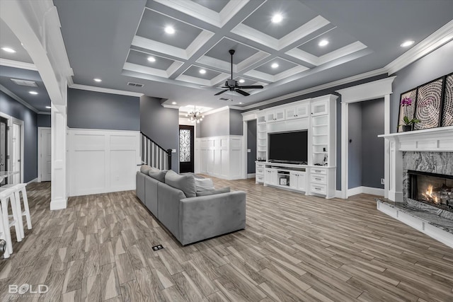 living room featuring visible vents, beam ceiling, light wood-style floors, a premium fireplace, and stairs