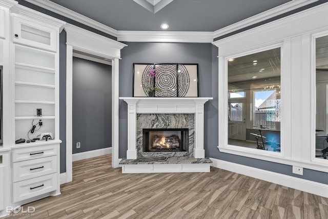 unfurnished living room featuring baseboards, recessed lighting, a high end fireplace, ornamental molding, and light wood-type flooring