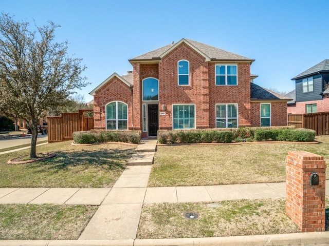 view of front of home featuring brick siding, roof with shingles, a front yard, and fence