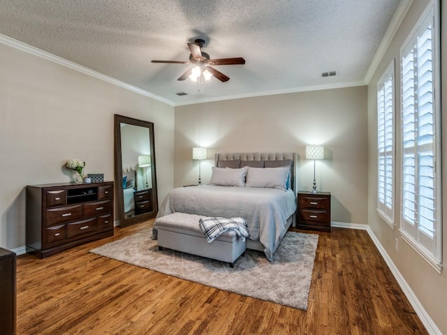 bedroom featuring ornamental molding, multiple windows, a textured ceiling, and wood finished floors