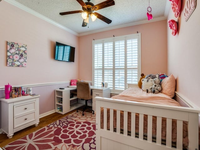 bedroom featuring a ceiling fan, ornamental molding, a textured ceiling, and wood finished floors