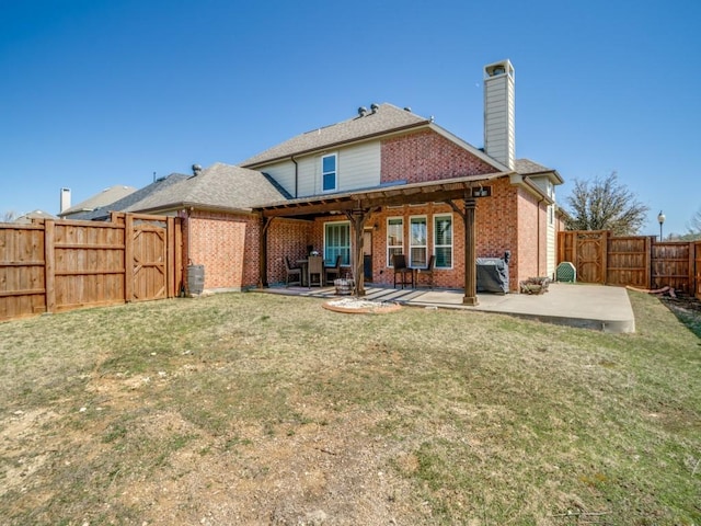 rear view of property with brick siding, a yard, and a patio