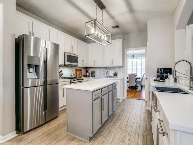 kitchen with tasteful backsplash, stainless steel appliances, light countertops, and light wood-style flooring