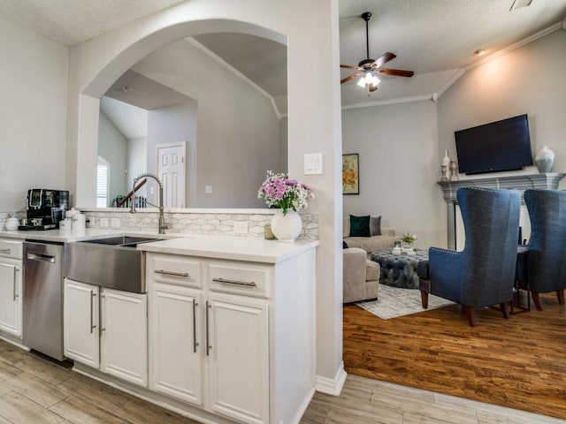 kitchen with wood finish floors, a sink, white cabinets, open floor plan, and dishwasher