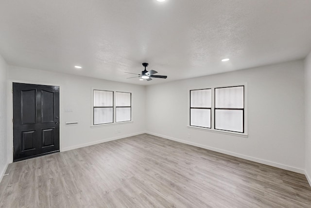 empty room featuring recessed lighting, light wood-style flooring, ceiling fan, a textured ceiling, and baseboards