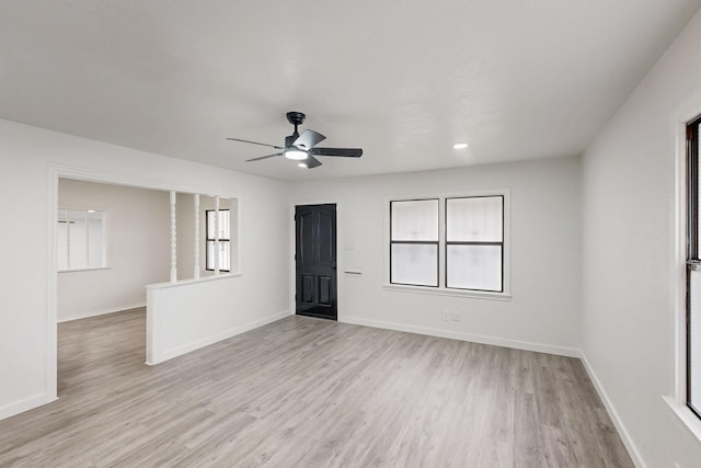 spare room featuring a ceiling fan, light wood-style flooring, and baseboards