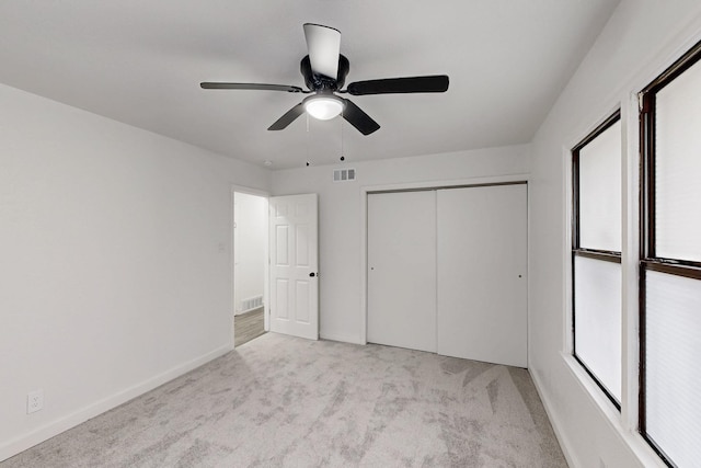 unfurnished bedroom with light colored carpet, a closet, visible vents, and baseboards