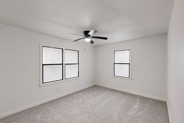 spare room featuring light colored carpet, ceiling fan, a textured ceiling, and baseboards