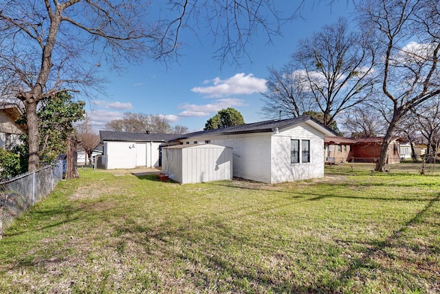 exterior space featuring an outbuilding, fence, a storage unit, a yard, and brick siding