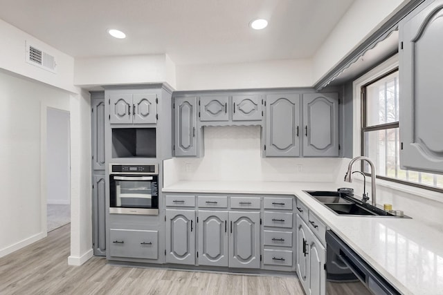 kitchen with visible vents, gray cabinets, a sink, and oven