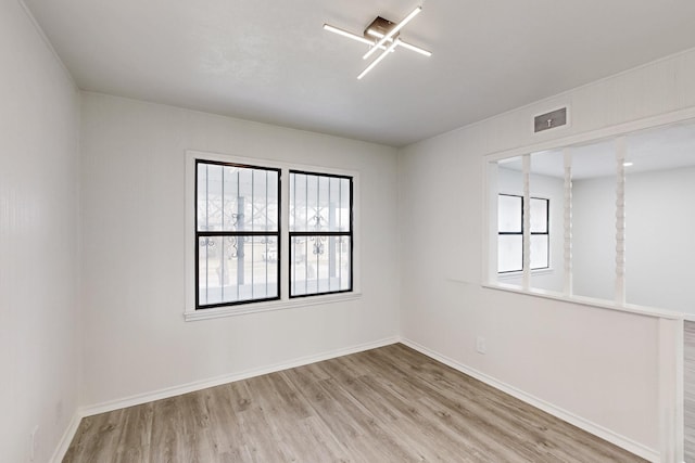 spare room with a healthy amount of sunlight, visible vents, baseboards, and light wood finished floors