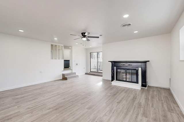 unfurnished living room featuring light wood-type flooring, a glass covered fireplace, visible vents, and recessed lighting