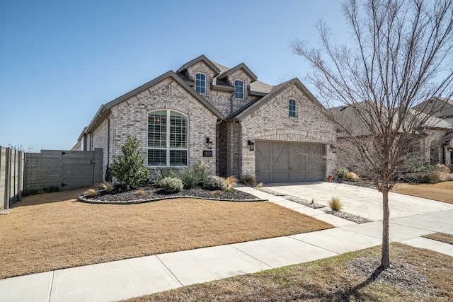 french provincial home featuring driveway, a garage, fence, a front lawn, and brick siding